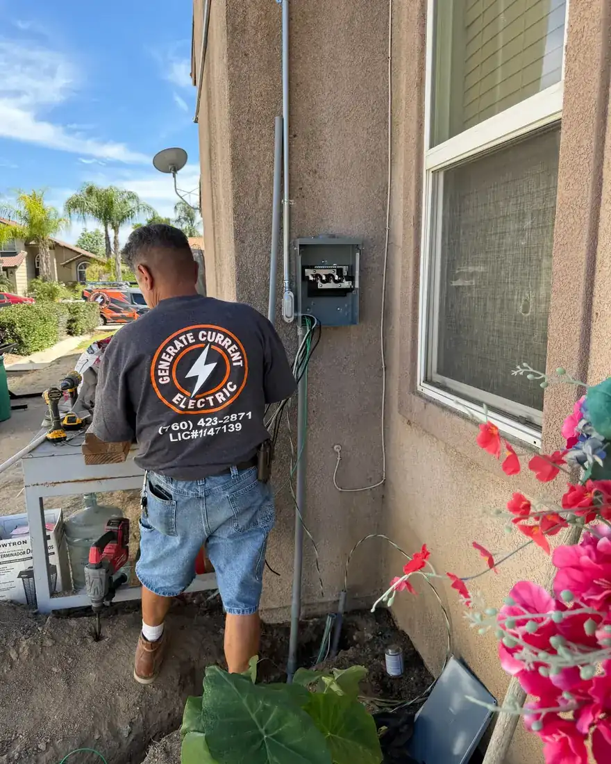 Generate Current Electric technician working at an exterior electrical panel.