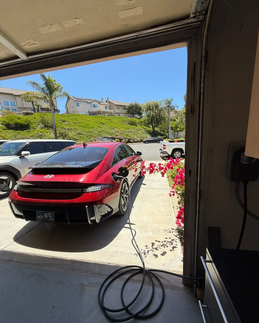 EV parked in an open garage charging from a wall-mounted Level 2 charger.