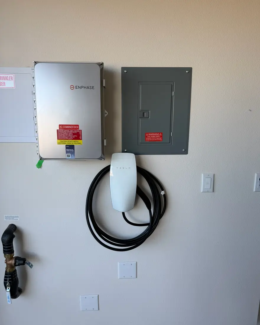EV charger fed from a dedicated disconnect and subpanel mounted on a garage wall.