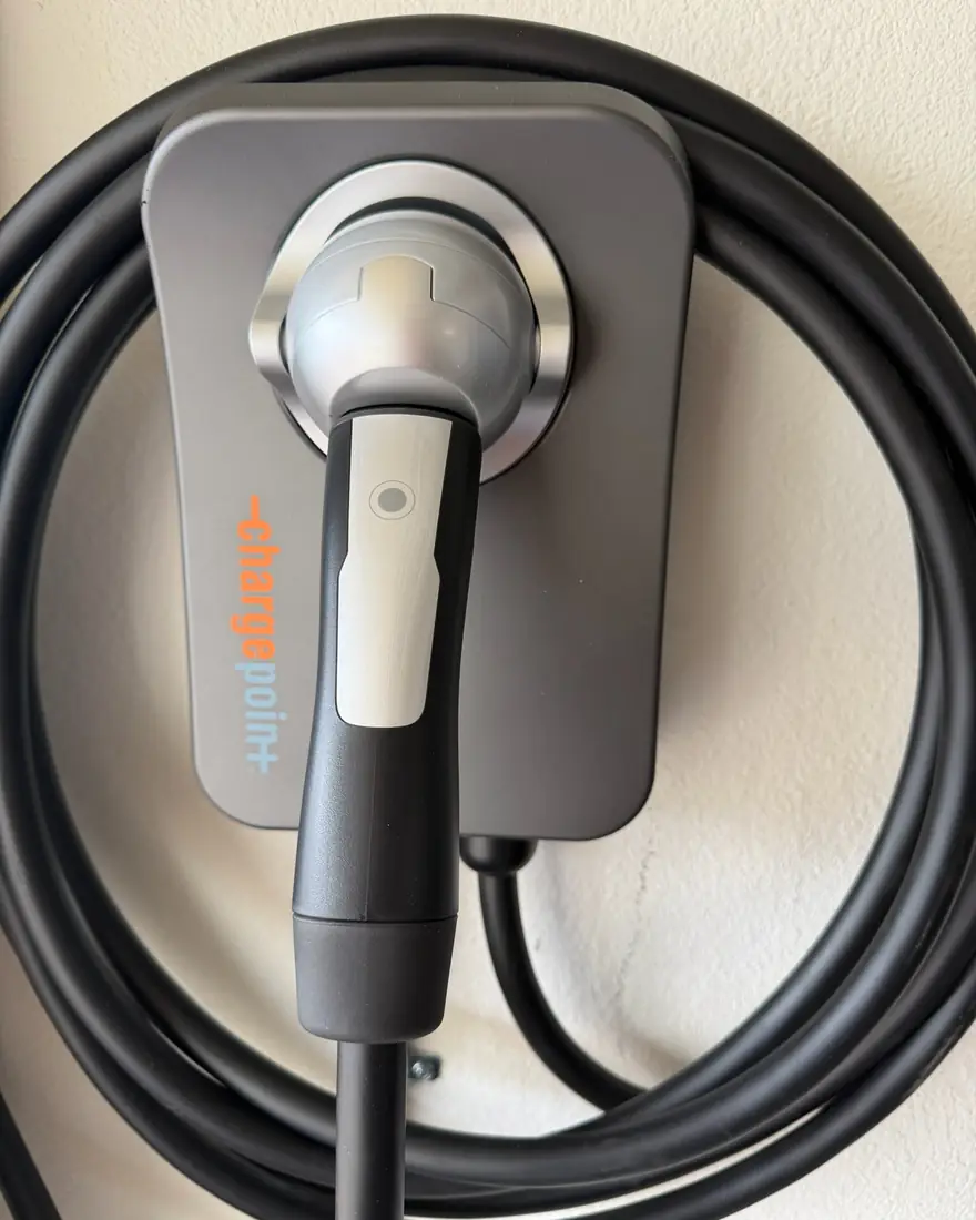 Non-Tesla Level 2 charging station mounted on a wall with its connector holstered.