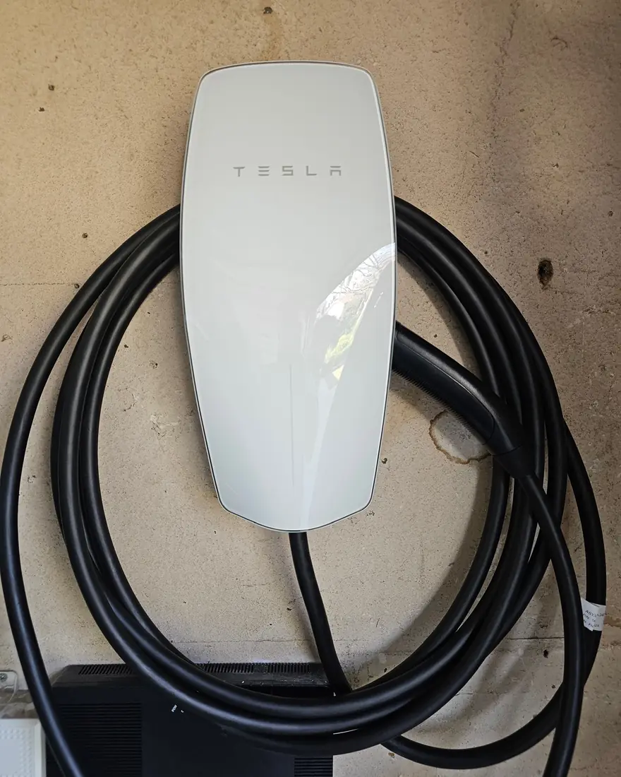 Wall-mounted EV charger with the charging cable coiled neatly on its hanger.
